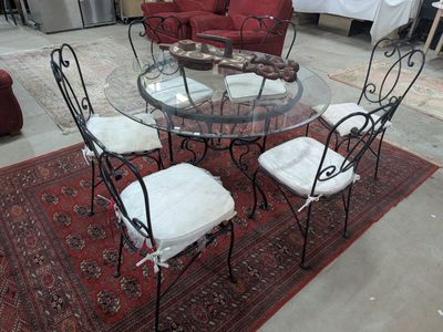 une table en verre avec quatre chaises et un tapis au sol