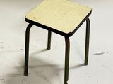 a small stool with a wooden top on a white floor