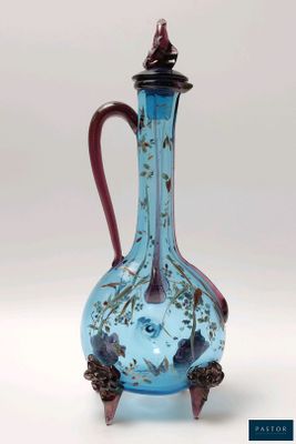 un vase en verre bleu muni d'une anse rouge, posé sur un socle