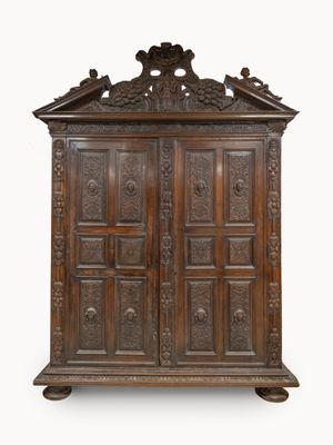 une vieille armoire en bois ornée de sculptures, notamment sur le dessus