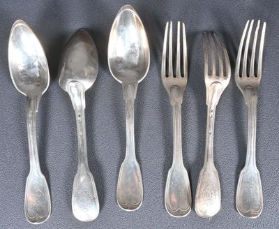 cinq cuillères en argent et deux fourchettes sont alignées sur une table