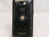 a black cell phone sitting on a stand on a white surface