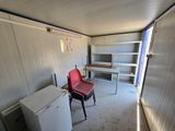 a red chair in the corner of a room with a white refrigerator