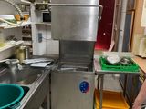 un homme debout dans une cuisine, près d'un évier