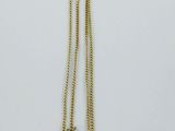 gros plan d'un collier en or sur une surface blanche