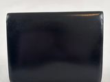 the black clutch bag is sitting on a white surface