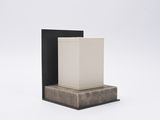 un vase blanc posé sur une boîte noire, sur une surface blanche