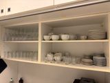 des étagères remplies de vaisselle et de verres dans une cuisine équipée de placards blancs