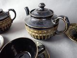 a black and gold tea set on a white table