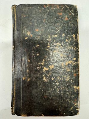 un vieux livre à la couverture noire posé sur une table