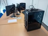 trois écrans d'ordinateur posés sur une table dans une pièce