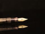 a fountain pen sitting on top of a black surface