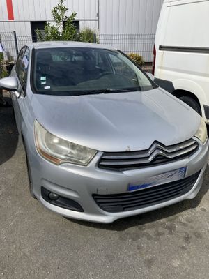 l'avant d'une Citroën argentée garée sur un parking à côté d'une camionnette blanche