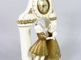 a white clock with a gold trim and a girl in a dress