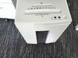 a white paper shredder sitting on the floor next to a black chair
