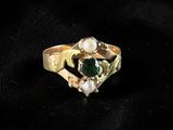 a close up of a gold ring with a green stone
