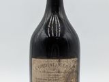 une vieille bouteille d'alcool posée sur une surface blanche
