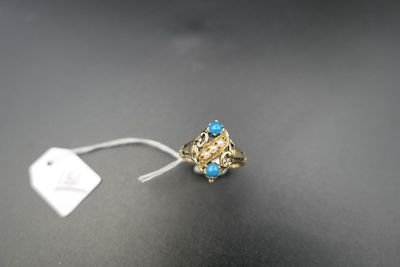 une bague en or sertie de pierres bleues et ornée d'une plaque, sur un fond noir