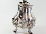 a silver tea pot on a stand on a white background