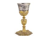une coupe en argent et en or posée sur un socle, sur fond blanc