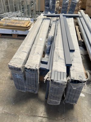 Plusieurs pièces d'acier sont empilées sur des palettes dans un entrepôt