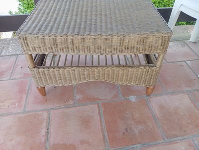 une table basse en osier sur une terrasse en briques