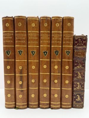 six vieux livres sont alignés sur une surface blanche