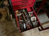 une boîte à outils rouge contenant des outils, dans un garage