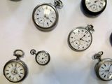 many different types of pocket watches displayed on a table