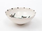 a white bowl with birds on it on a white surface