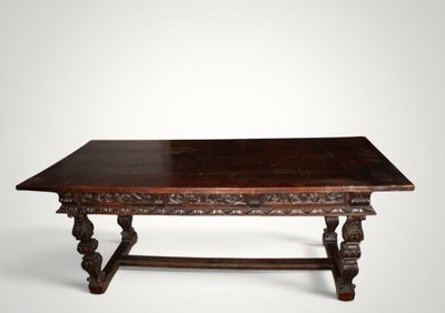 une vieille table en bois aux pieds sculptés et au plateau en bois