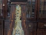 a grandfather clock sitting on the floor in front of a bookcase