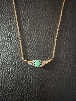 un collier en or orné d'une pierre verte, monté sur un cordon en cuir noir