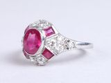un gros plan d'une bague sertie d'un rubis et de diamants sur une surface blanche