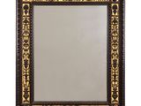 un miroir à cadre noir et doré orné d'un motif décoratif