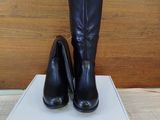 black leather high heeled boots on top of a white box