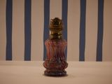 a red glass bottle with a gold top on a table