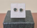 une paire de boucles d'oreilles à clous ornées d'émeraudes, exposées sur un bloc de marbre