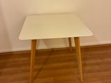 une table blanche aux pieds en bois, dans un coin de la pièce