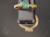 un gros plan d'une bague en or sertie de deux émeraudes