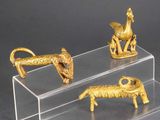 trois figurines d'animaux en or posées sur un socle transparent