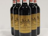 four bottles of red wine are lined up on a white surface
