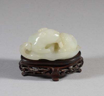 une petite sculpture blanche représentant un chien, posée sur un socle en bois