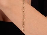 a close up of a woman ' s arm wearing a gold chain bracelet