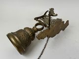 an old brass bell hanging from a chain on a white surface