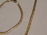 a gold necklace and a gold bracelet on a table