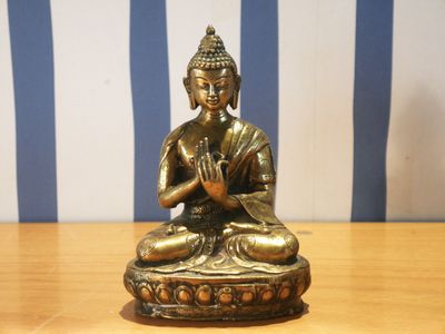 statue représentant une personne assise en position du lotus sur une table en bois