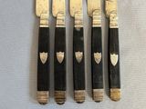 four knives with black handles and a silver handle on a table