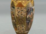 a gold vase with a painting on it on a table
