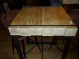 a wooden table with four stools and a picture on the wall
